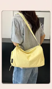 Close-up of lightweight nylon crossbody bag with wide shoulder strap and brand label