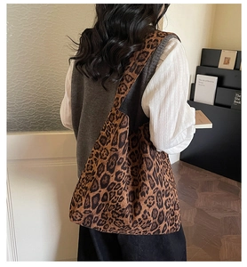 Close-up of a large leopard print suede tote bag worn by a model in a minimalist room