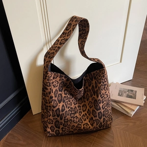 Large leopard print suede tote bag with retro shoulder strap on a wooden floor