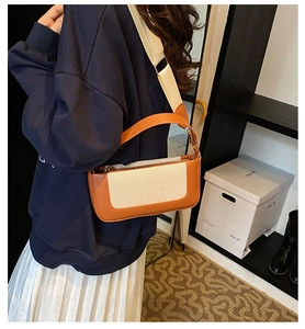 Model wearing a stylish contrast canvas and orange leather shoulder bag for city lifestyle