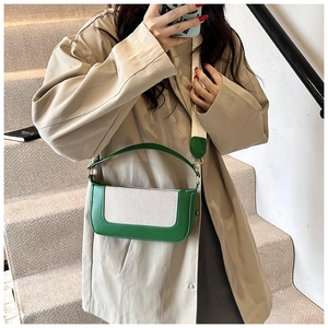 Detail view of a green contrast small square bag styled with a beige trench coat