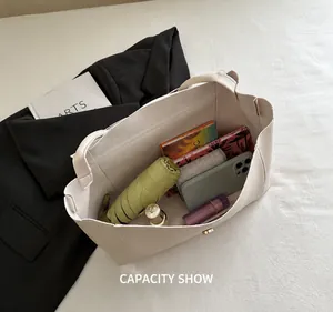 Détail montrant la grande capacité intérieure de ce sac cabas crème avec des objets quotidiens