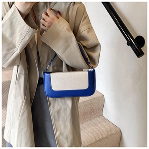 Chic blue and beige patchwork shoulder bag shown on a model in an elegant city setting