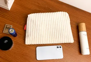 Détail de la texture d'une pochette en velours côtelé blanc et étiquette fashion