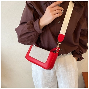 Close-up of red leather and white canvas crossbody bag shown on a model