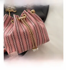 Détail du sac seau tissé rose avec motif à chevrons noirs et chaîne ornée de perles