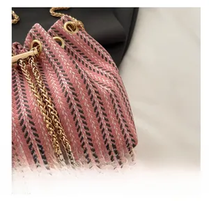 Détail du sac seau à chevrons rose et blanc avec chaîne dorée et breloques en perles