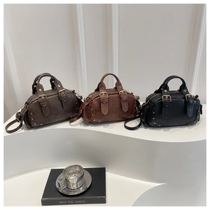 Three vintage Boston bags in brown and black on a white display stand with metal hardware