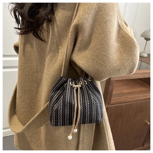 Détail du sac seau tissé avec pompons de perles élégants et bandoulière chaîne dorée