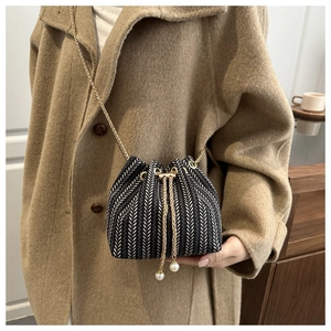 Gros plan du sac seau à chevrons noir et blanc avec chaîne dorée et détails de perles chic