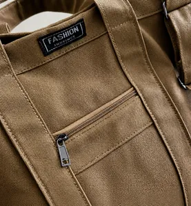 Detail van bruine canvas tas met geweven label en versterkte stiksels voor duurzaamheid