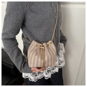 Détail du sac seau tissé avec chaîne dorée et élégants pendentifs en perles au cordon