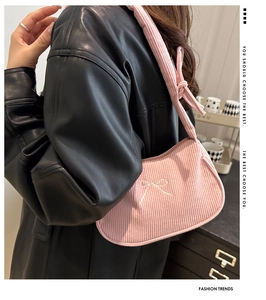 Detail of pink corduroy shoulder bag with bow embroidery and stylish knotted strap