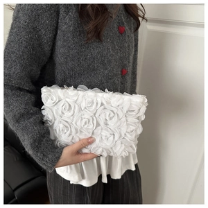 Detail of white 3D rose lace evening clutch bag held against a grey sweater