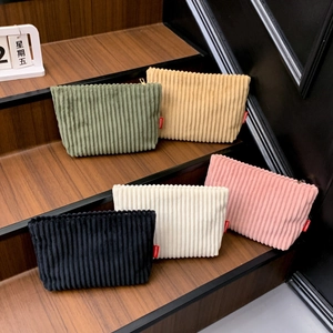 Pochettes enveloppes en velours côtelé en cinq couleurs sur un support en bois