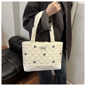 Dettaglio della borsa tote trapuntata bianco off-white con ricami a fiocco nero e fiocco in metallo