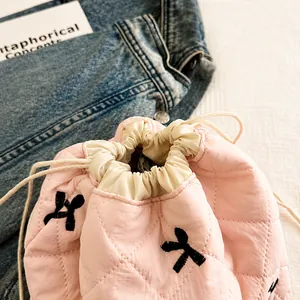 Detail of pink quilted drawstring bucket bag with rhombus stitching and embroidery