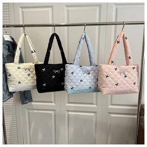 Bolsos tote acolchados en cuatro colores con lazos decorativos en una percha