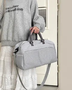 Borsa sportiva grigio chiaro con scomparto a rete e manici viola tenuta da una modella