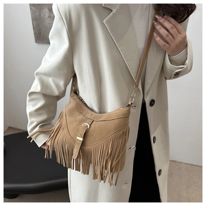 Detail of camel suede tote bag with fringe tassels and metal buckle on model