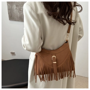 Detail of caramel brown suede tote bag featuring bohemian tassels and a gold buckle strap