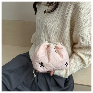 Detail of pink quilted bucket bag with black bow embroidery and drawstring closure