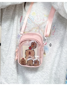 Detail of pink crossbody bag with transparent PVC window and cute capybara badges