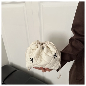 Détail d'un sac seau en nylon matelassé blanc avec broderie nœud noir et cordon de serrage