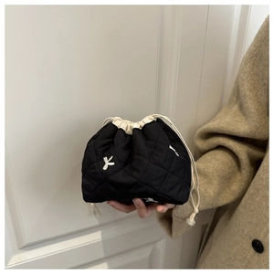 Detail of black quilted drawstring bucket bag featuring white butterfly embroidery and textures