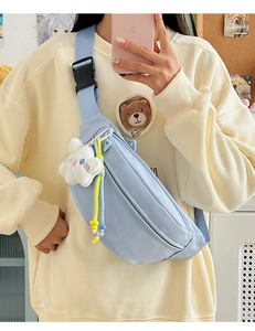 Detail of light blue nylon chest bag featuring a white cloud plush charm and adjustable strap