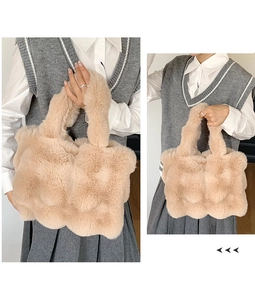 Detail of beige faux fur tote bag showing wave texture and plush material on model