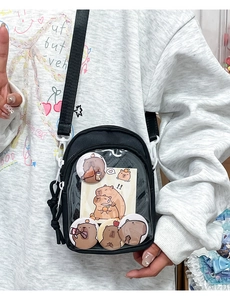 Detail of black ita bag featuring transparent window with cute capybara badges