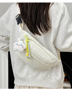 Detail of ivory crescent crossbody bag with thick strap and cute plush charm pendant