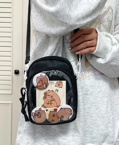 Detail of black ita bag with transparent window showing capybara badges and charms