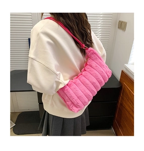Detail of pink faux fur shoulder bag with horizontal quilted texture shown on a model