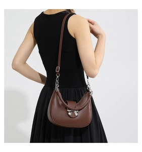 Rear view of model wearing a brown crescent handbag with a silver bow buckle and long strap