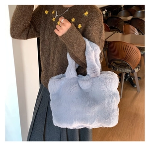 Detail of soft lavender plush faux fur tote bag held by a model in a cozy cafe setting