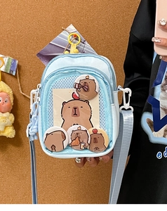 Detail view of light blue Ita bag with clear PVC window showing Capybara badges