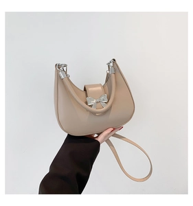 Detail of apricot crescent handbag featuring a matte leather finish and silver bow clasp