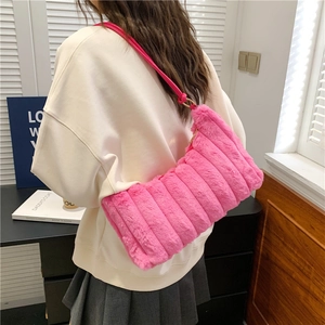 Detail of bright pink plush shoulder bag with vertical stripes and golden metal rings