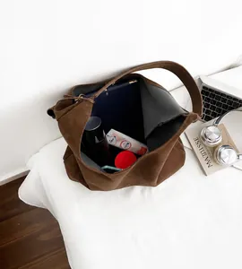 Macro detail of spacious interior in coffee brown suede tote bag with daily essentials