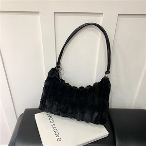 Detail of black faux fur shoulder bag with plush striped texture and leather strap