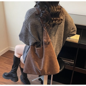 Detailed texture of brown faux suede tote bag featuring debossed branding and matte finish