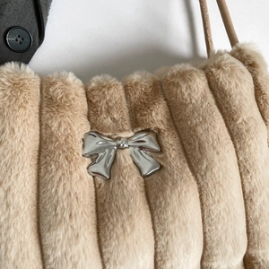 Detailaufnahme der Plüsch-Tasche mit silberner Metallschleife und vertikalen Streifen