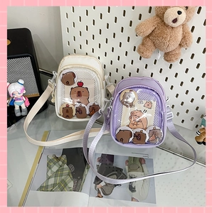 Detail of white and purple Ita bags with clear PVC windows and Capybara theme badges