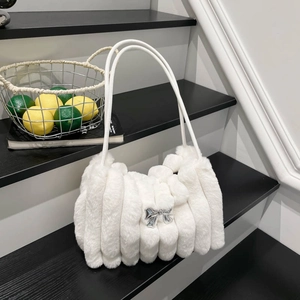 Detail der weißen Plüsch-Tasche mit vertikalen Falten und silberner Schleife auf Treppen