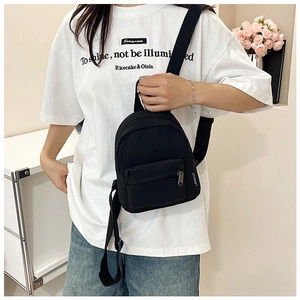 Dettaglio mini zaino nero in nylon con tasca frontale a zip ed etichetta laterale logo