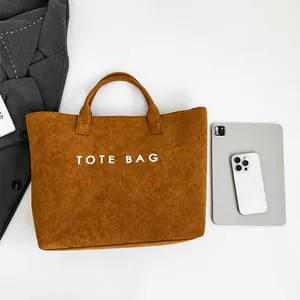 Καφέ σουέτ τσάντα tote δίπλα σε tablet για την ανάδειξη της μεγάλης χωρητικότητάς της