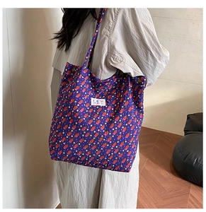 Detail van paarse gewatteerde tote bag met bloemenprint, drukknopen en een logo-patch