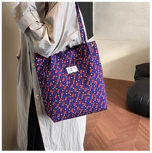 Detail van paarse bloemen shopper met bubble textuur stof en een geweven merklabel